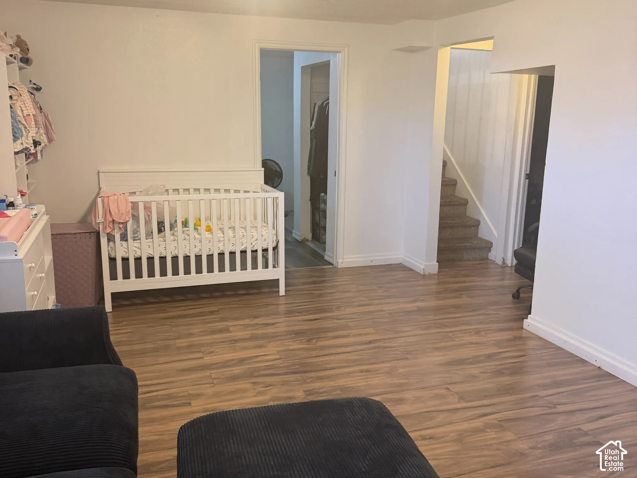 Wood-finish flooring throughout, with a flush-mount ceiling light fixture, and a staircase with white risers and handrail
