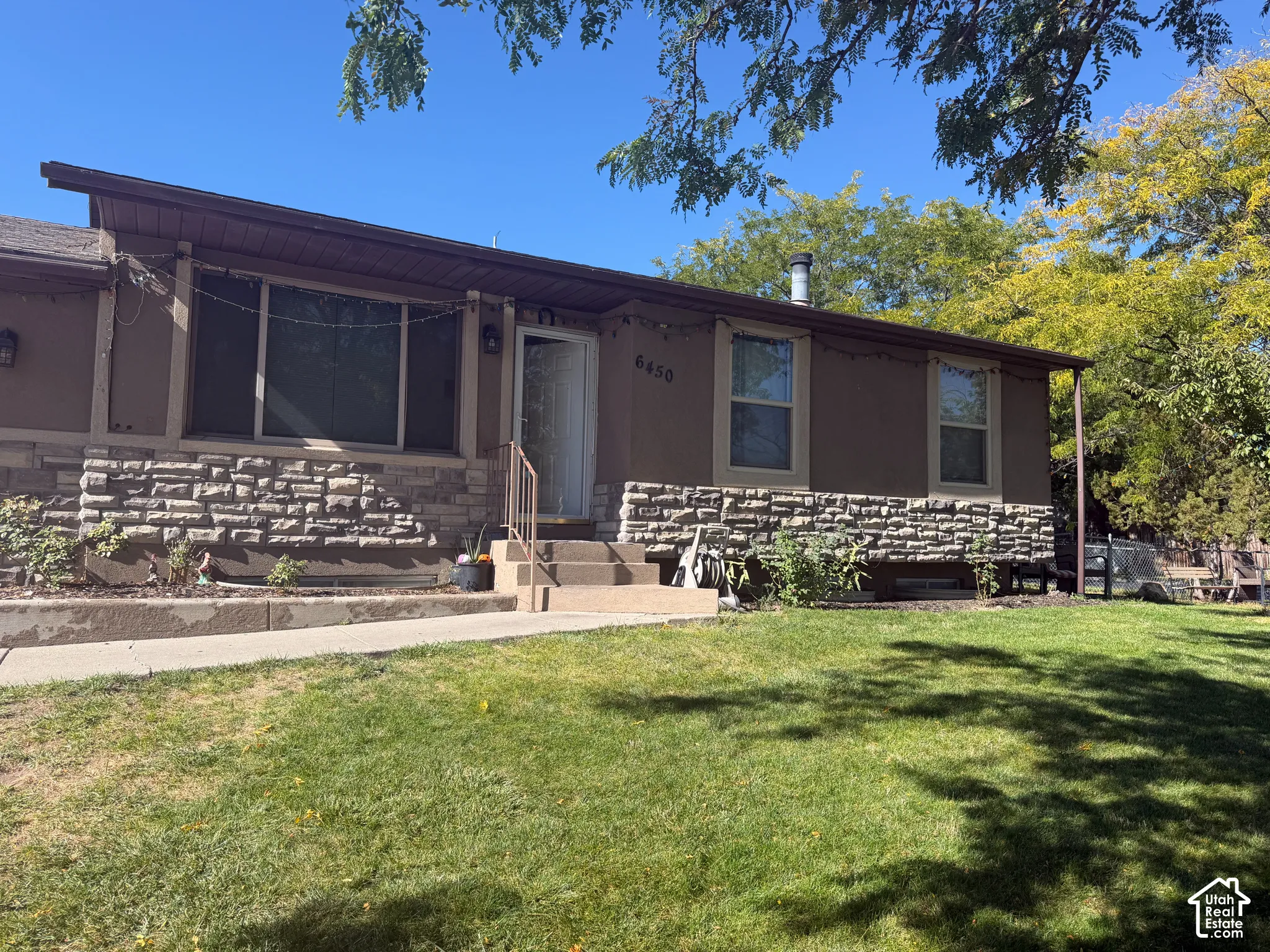 Exterior featuring a stone facade, stucco siding, a covered entry, and a sloped roofline