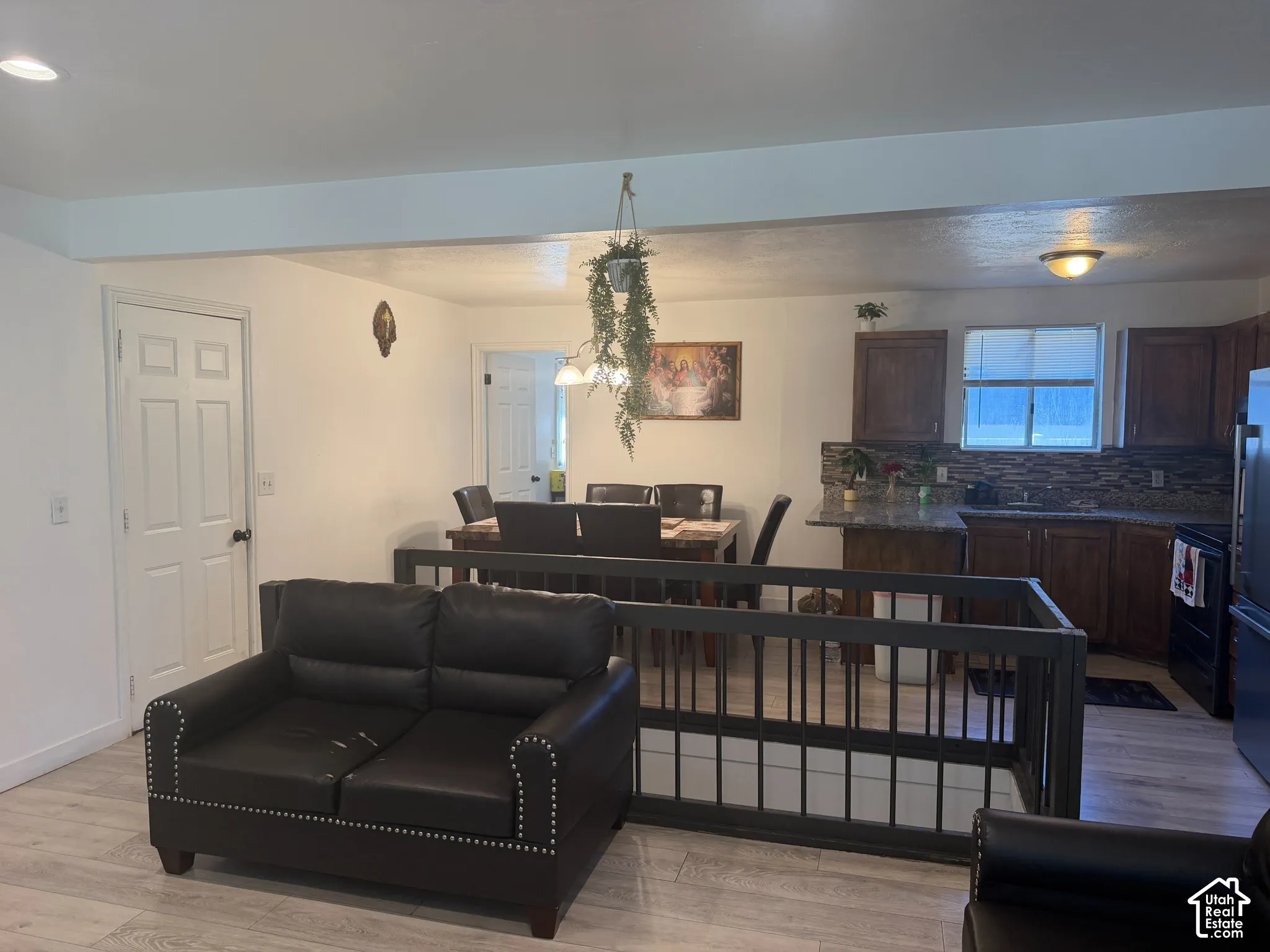 Wood-finish flooring throughout, with a kitchen featuring dark wood cabinetry, granite countertops, and a full backsplash