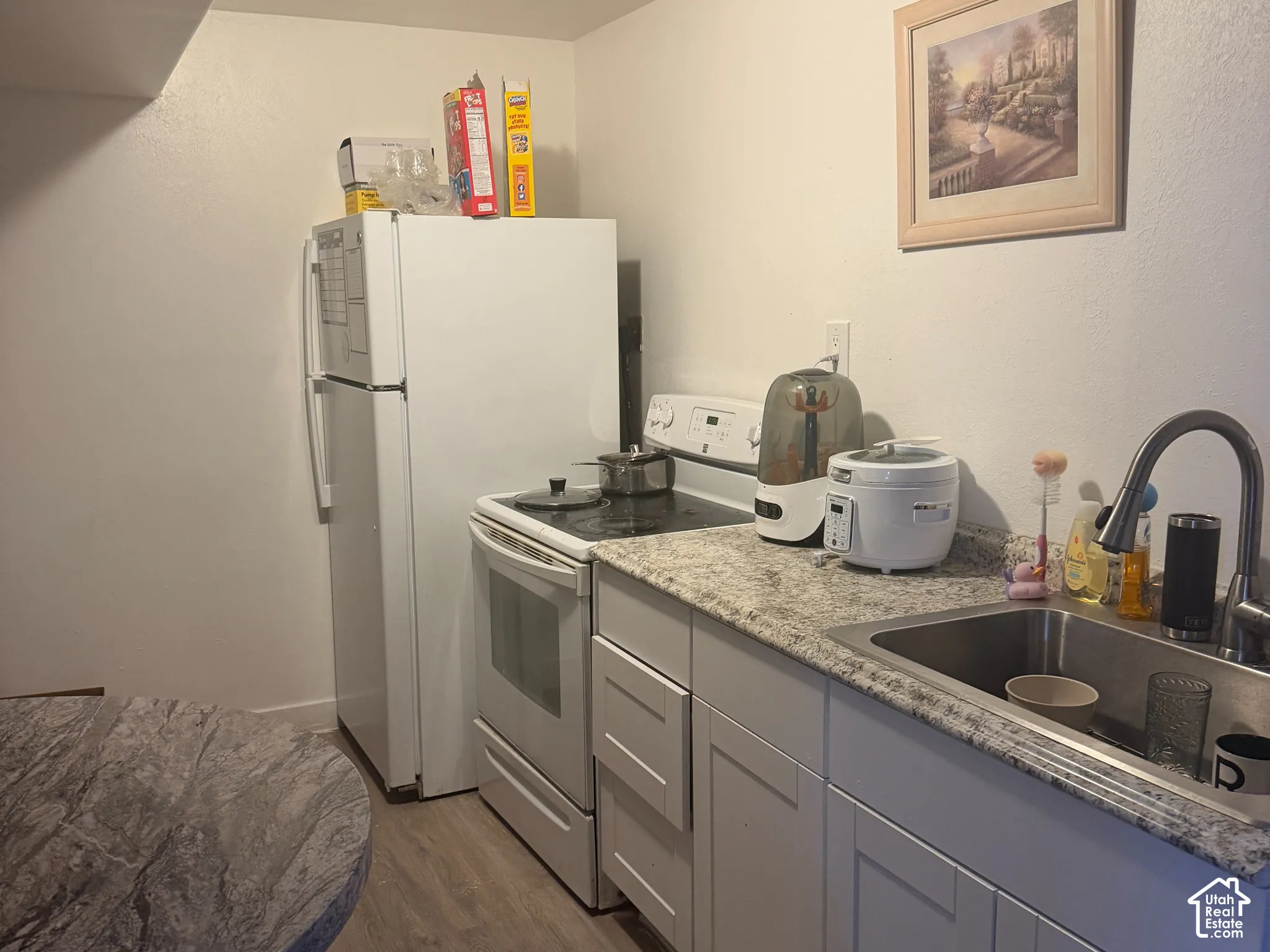 Kitchen featuring a refrigerator, electric range, stainless steel sink, and gray cabinetry