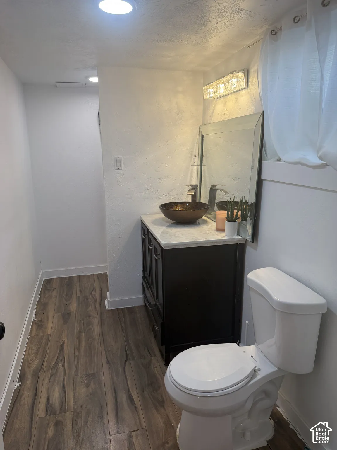 Dark wood-finish flooring, white walls, and recessed lighting