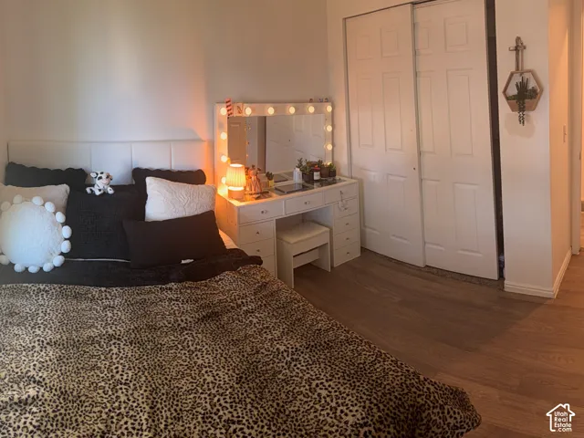 Light wood-finish flooring, white walls, and a window with a dark roller shade
