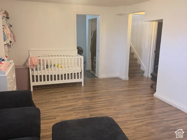 Wood-finish flooring throughout, with a flush-mount ceiling light fixture, and a staircase with white risers and handrail
