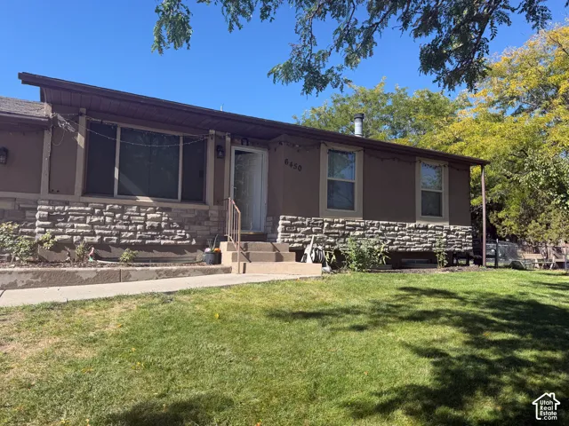 Exterior featuring a stone facade, stucco siding, a covered entry, and a sloped roofline