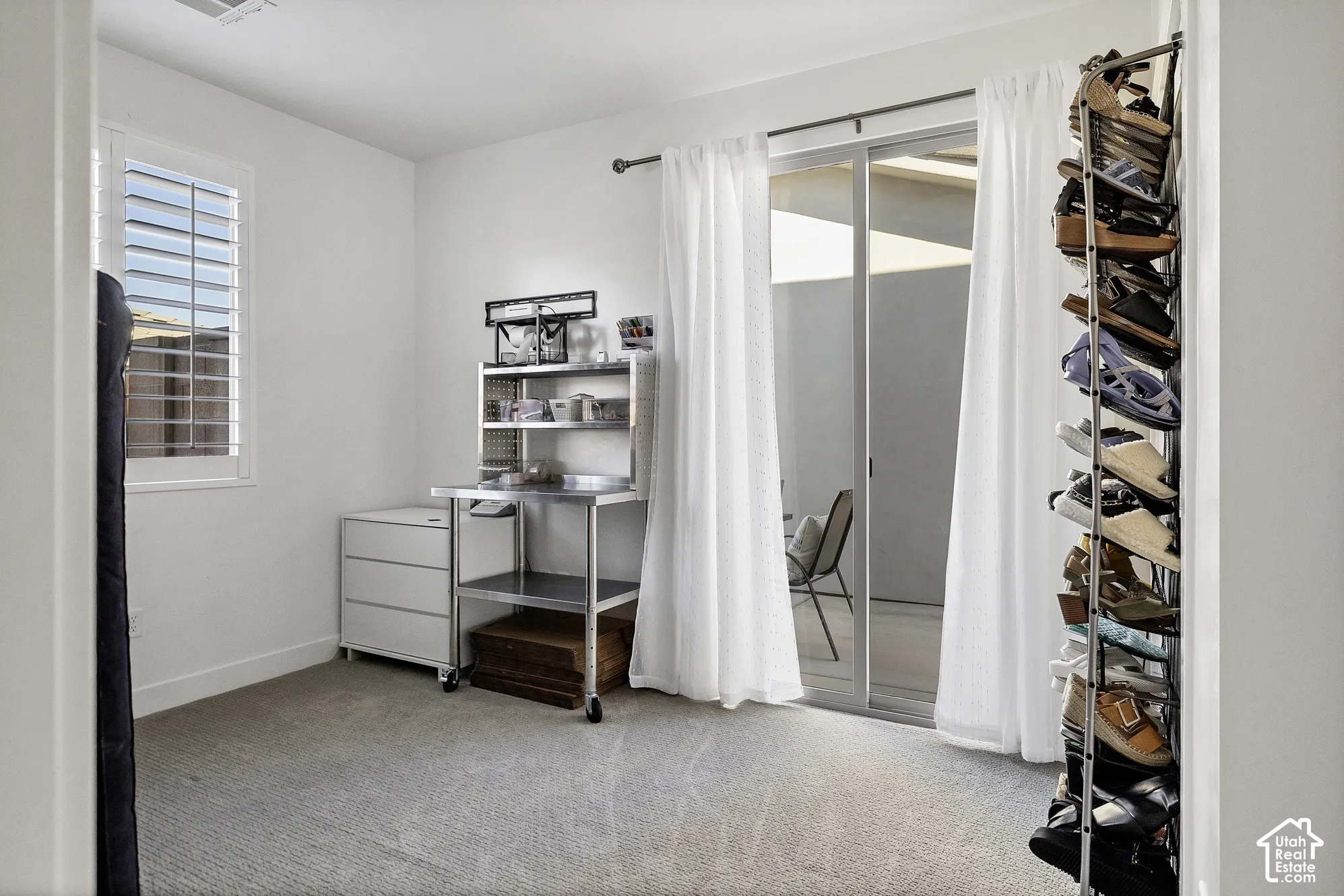 Light-colored carpeting, white walls, and a window with white plantation shutters