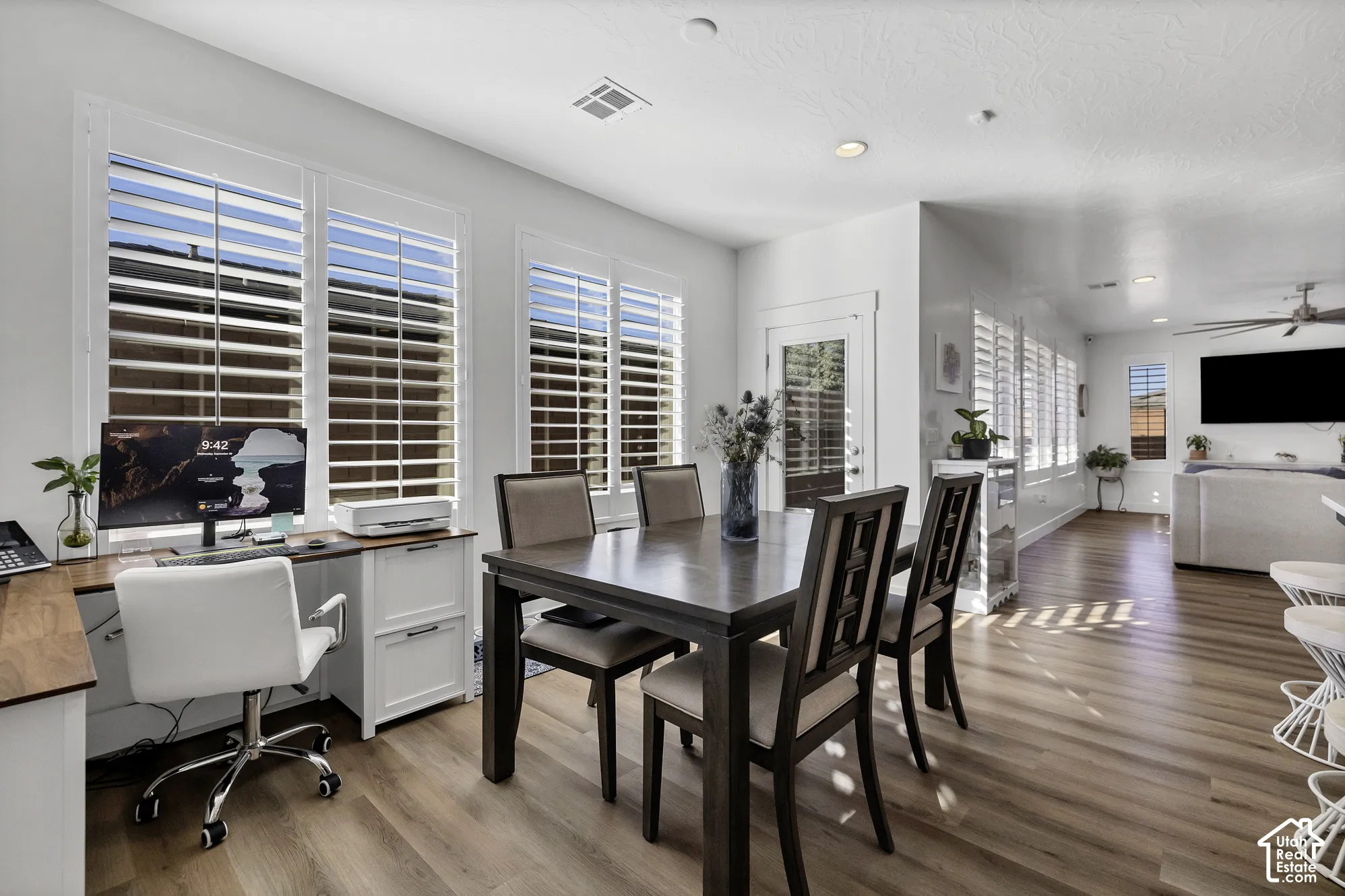 Wood-finish flooring throughout, white plantation shutters, recessed lighting, and a white paneled door