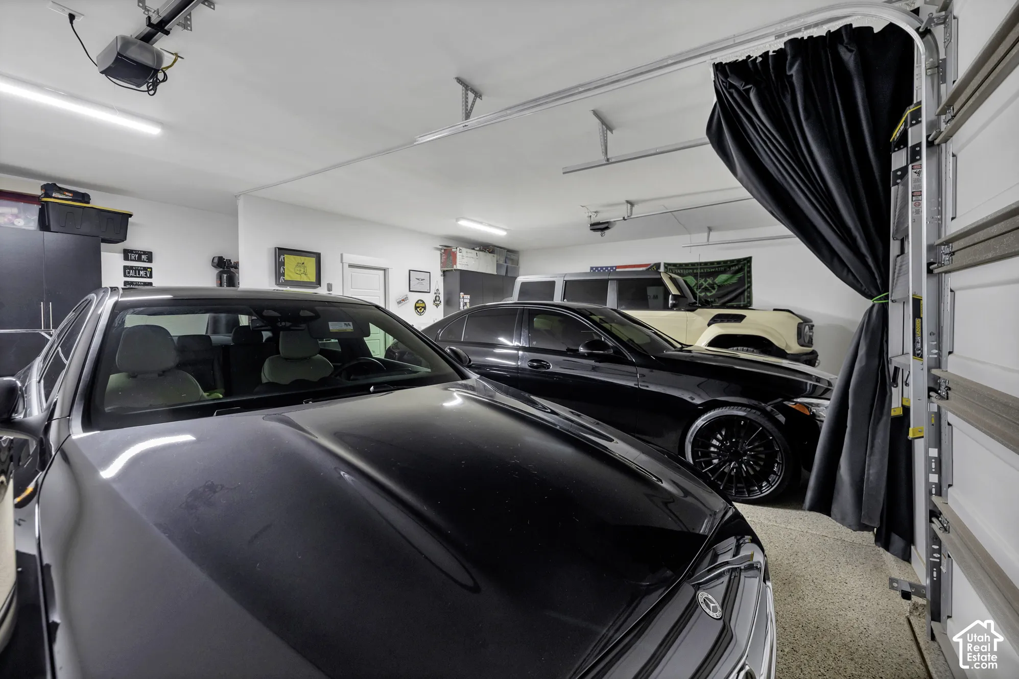 Epoxy-coated flooring, white walls, overhead lighting, garage door track system, and built-in dark cabinetry