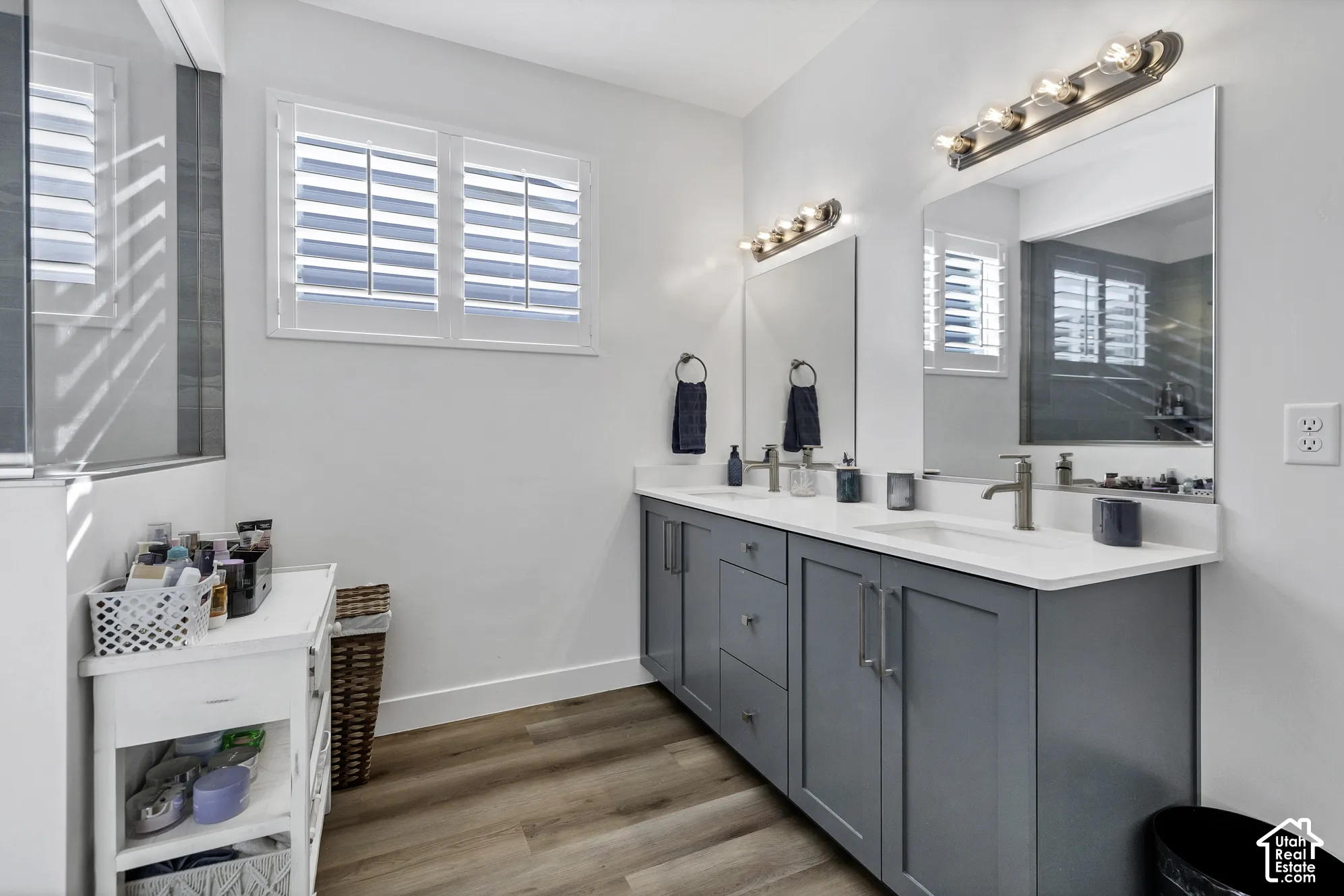 Dual vanity with gray cabinetry, white countertops, and brushed nickel fixtures