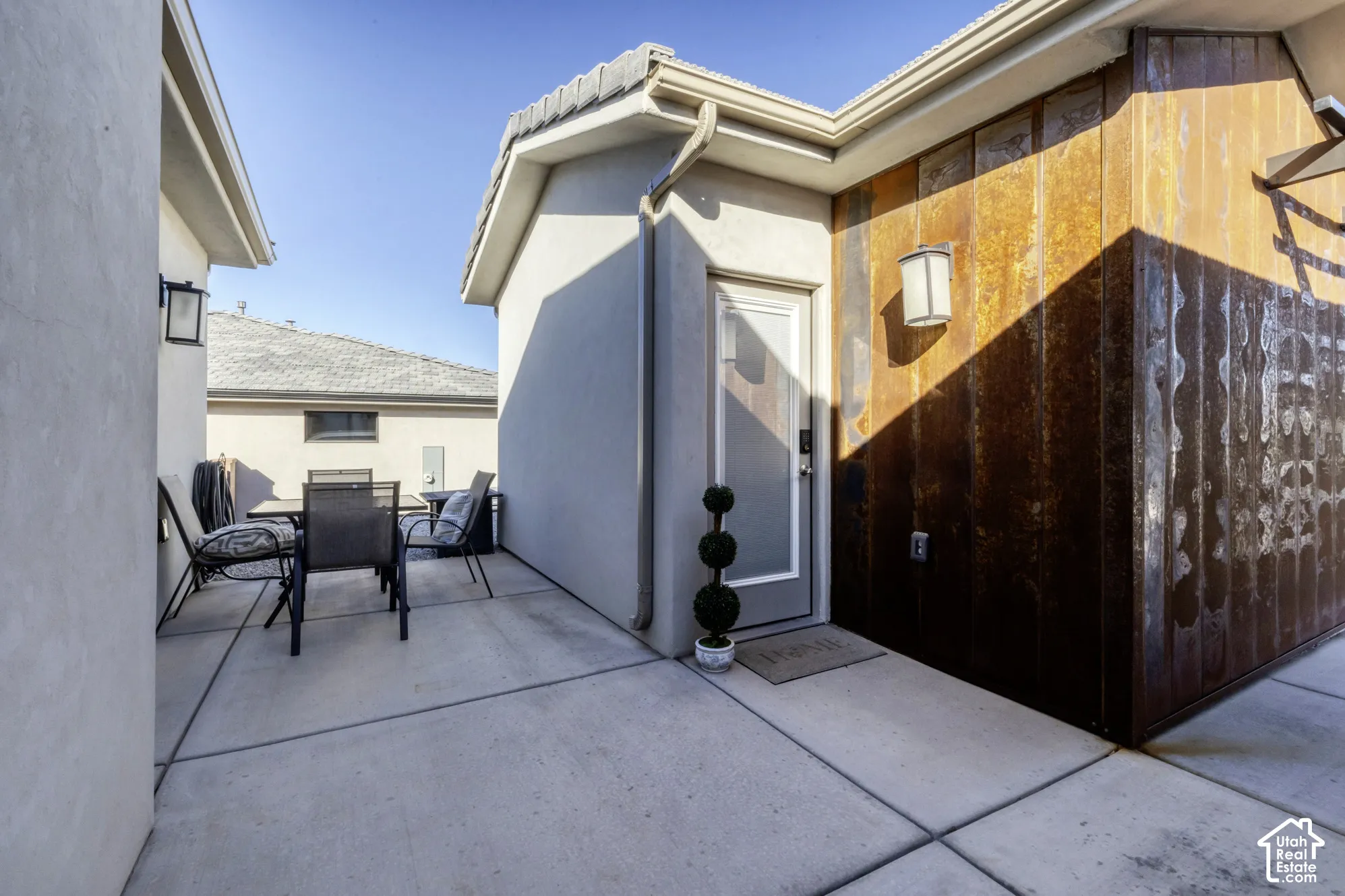 Concrete patio with accent wall featuring corrugated metal siding and a frosted glass-panel door