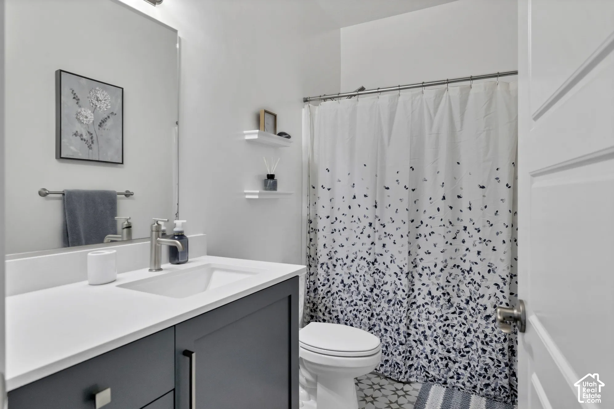 Bathroom featuring a single vanity with dark cabinetry, integrated sink, and brushed nickel faucet