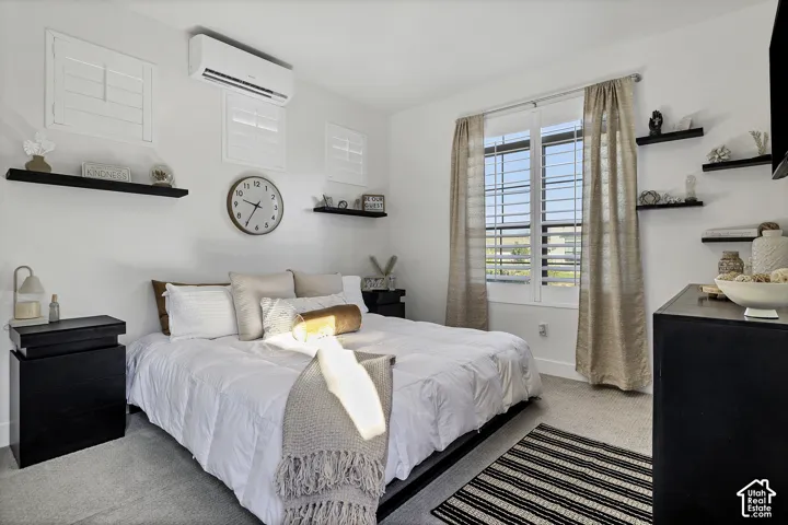 Casita window with louvered shutters, wall-mounted air conditioning unit, built-in shelving, light gray carpeting, and white walls