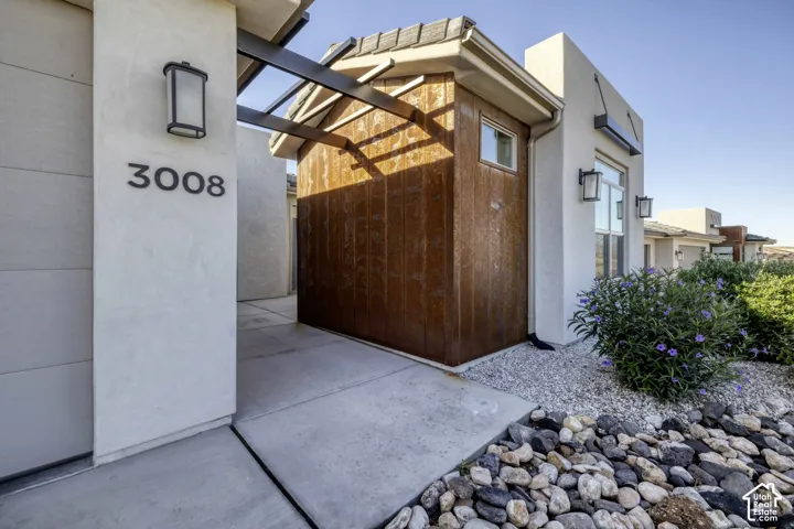 Stucco exterior with modern house numbers, contemporary outdoor lighting, and a metal-clad architectural feature