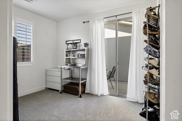 Light-colored carpeting, white walls, and a window with white plantation shutters