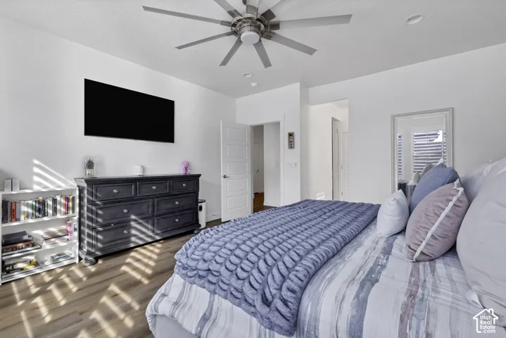 Wood-finish flooring, ceiling fan, recessed lighting, and a white interior door