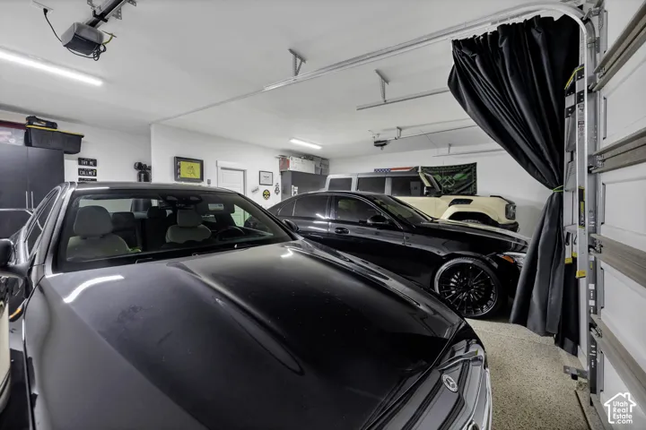 Epoxy-coated flooring, white walls, overhead lighting, garage door track system, and built-in dark cabinetry