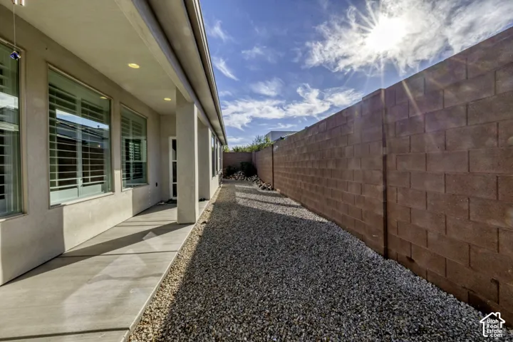 Stucco exterior with a covered patio, recessed lighting, and expansive windows featuring plantation shutters