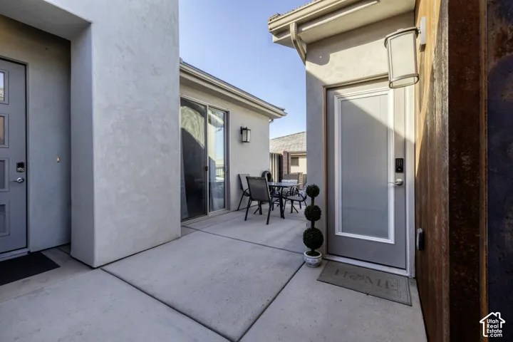 Concrete patio area featuring two exterior doors with frosted glass panels, a sliding glass door, and stucco wall finishes