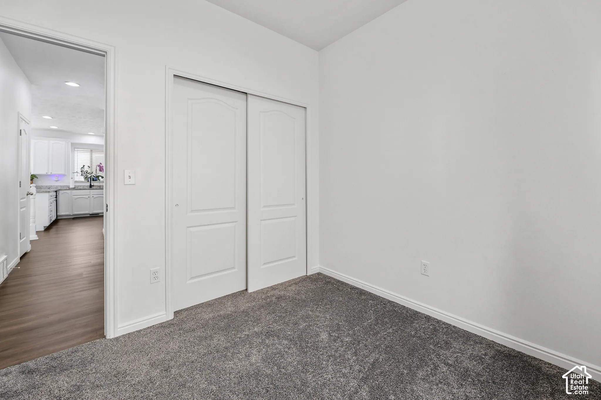 Spacious bedroom featuring neutral walls, gray carpet flooring, and a double closet with white sliding doors