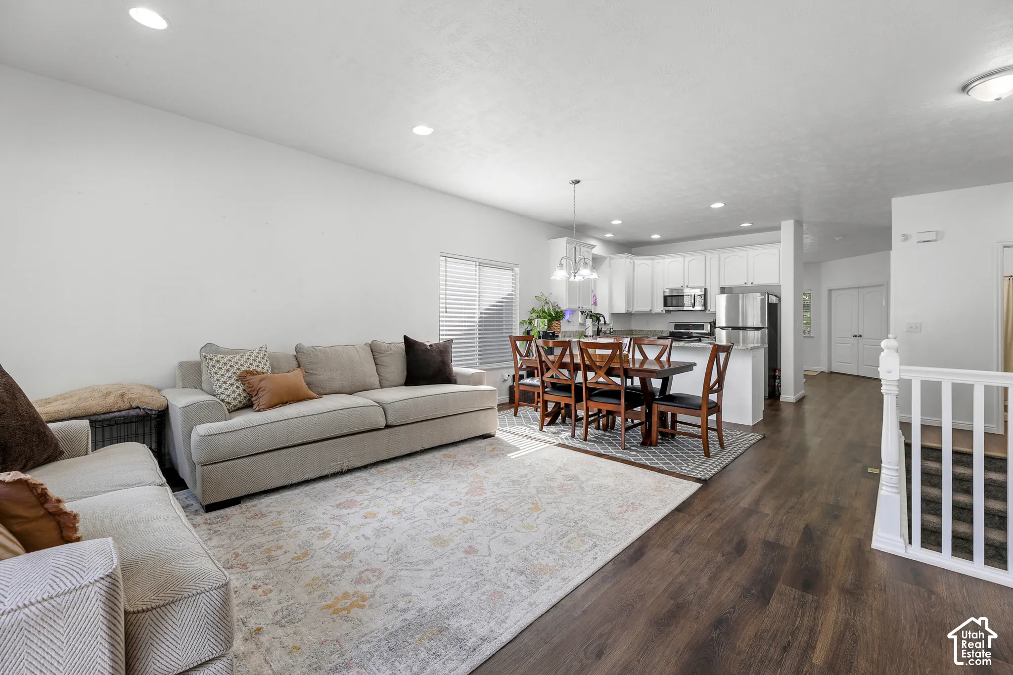 Open-concept living space featuring a gray upholstered sofa, wood-finish flooring throughout, and recessed ceiling lighting