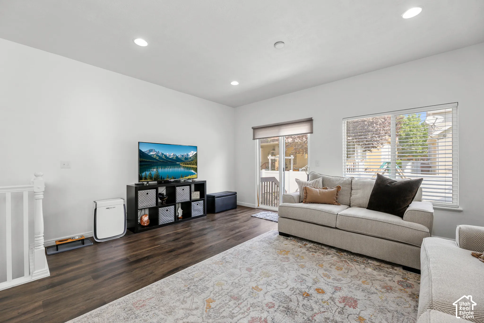 White wall finishes, wood-finish flooring, recessed lighting, white window frames, and a sliding glass door