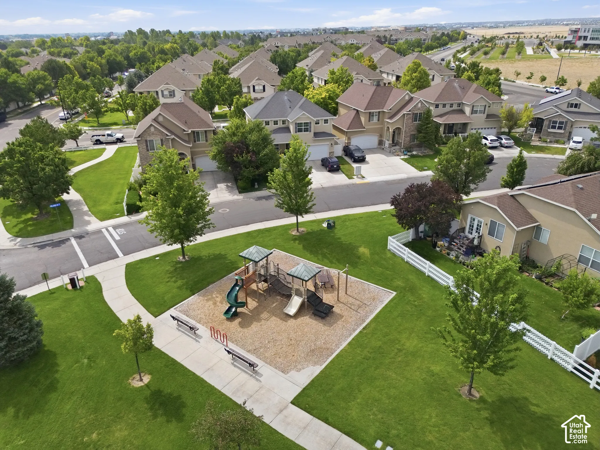 Expansive backyard oasis featuring a custom playground with rubberized safety surfacing, mature landscaping with established trees, manicured lawn, and concrete hardscaping