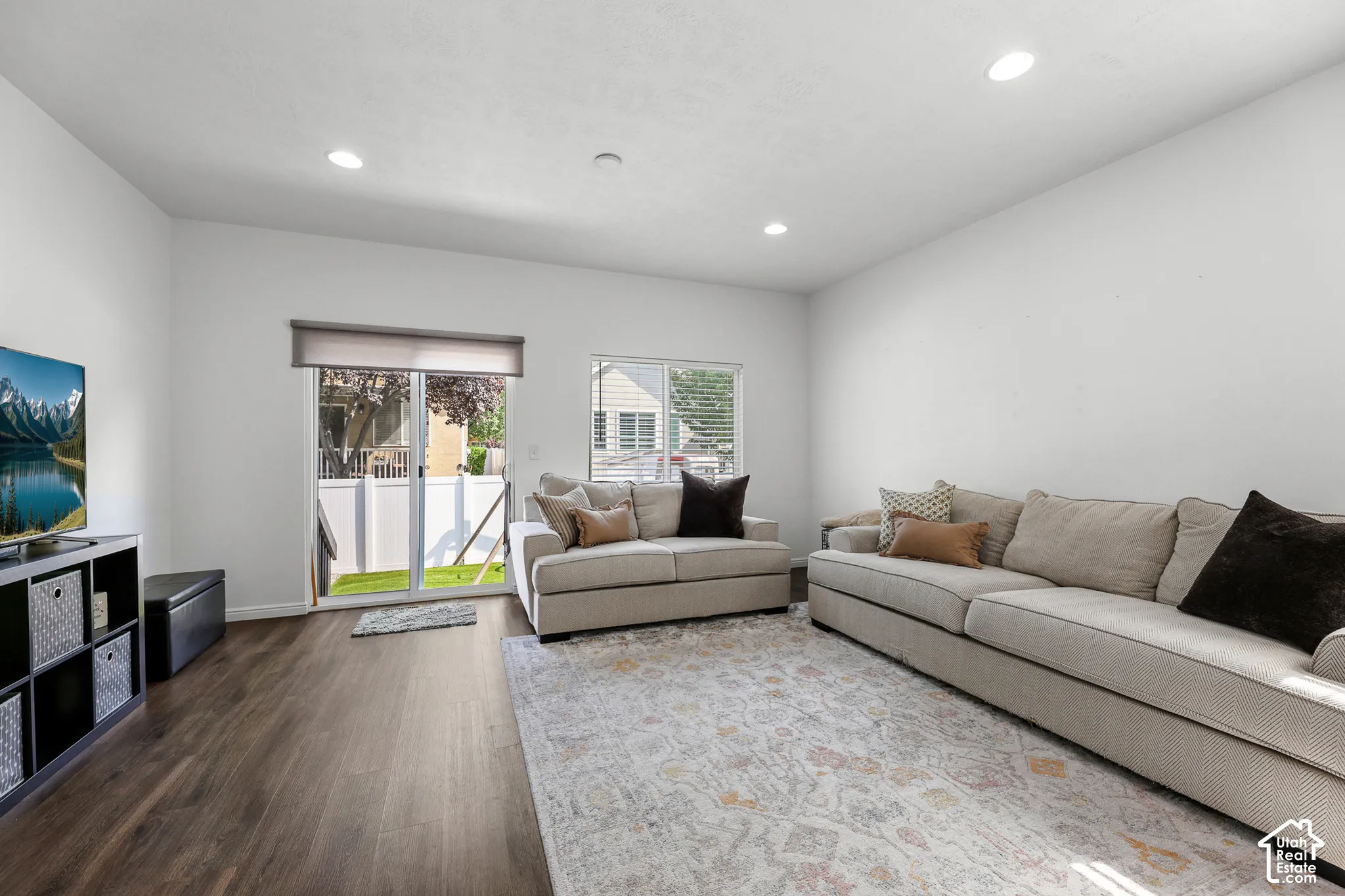 Recessed lighting, wood-finish flooring, sliding glass door, privacy fencing, and window with blinds