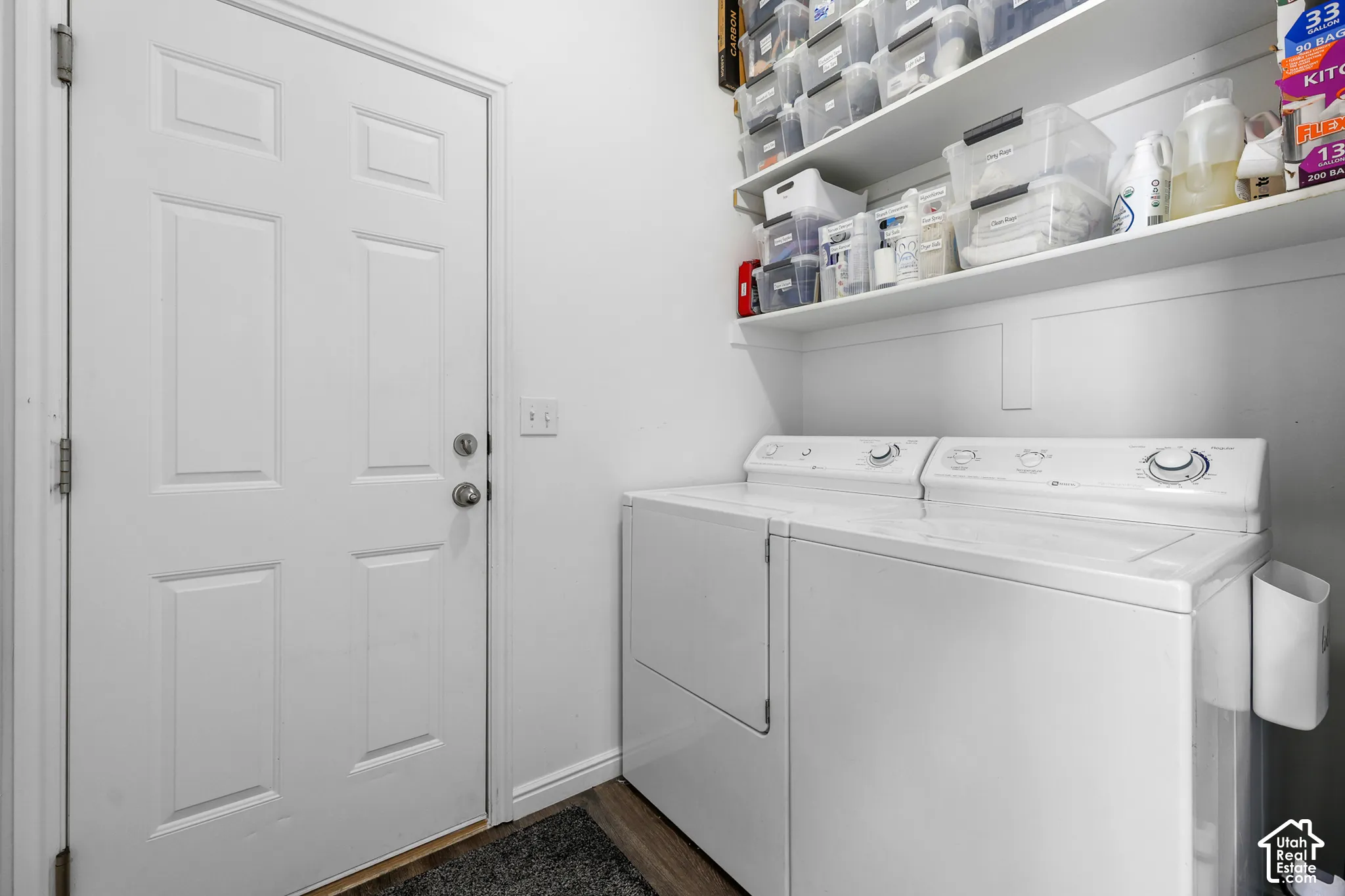 White paneled door, built-in shelving, wood-finish flooring, and white walls