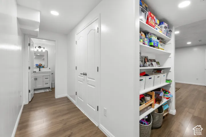 Bright hallway with wood-finish flooring, white six-panel closet doors, and recessed lighting