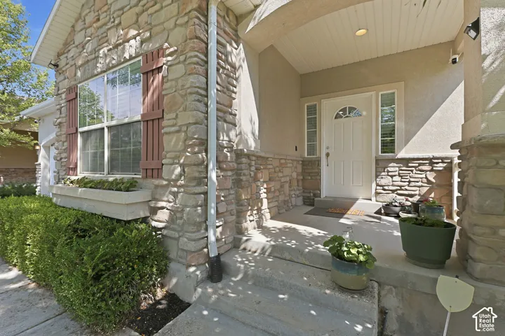 Stone and stucco exterior with a covered front entry featuring a white painted door, sidelight windows, and decorative stone accents