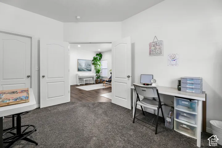 Double doors opening to an adjacent room, gray carpeting, and white walls