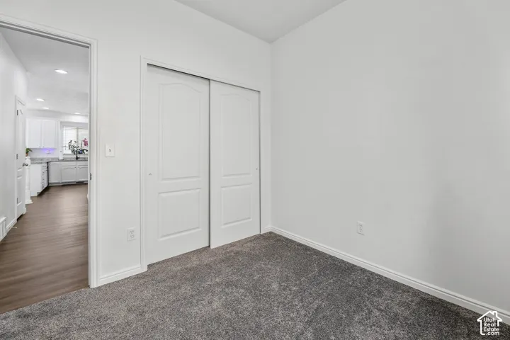 Spacious bedroom featuring neutral walls, gray carpet flooring, and a double closet with white sliding doors