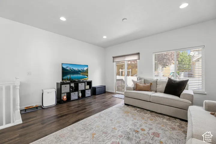 White wall finishes, wood-finish flooring, recessed lighting, white window frames, and a sliding glass door
