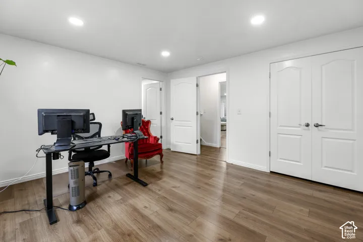 Recessed ceiling lighting, wood-finish flooring, white walls, and multiple panel doors with brushed nickel hardware