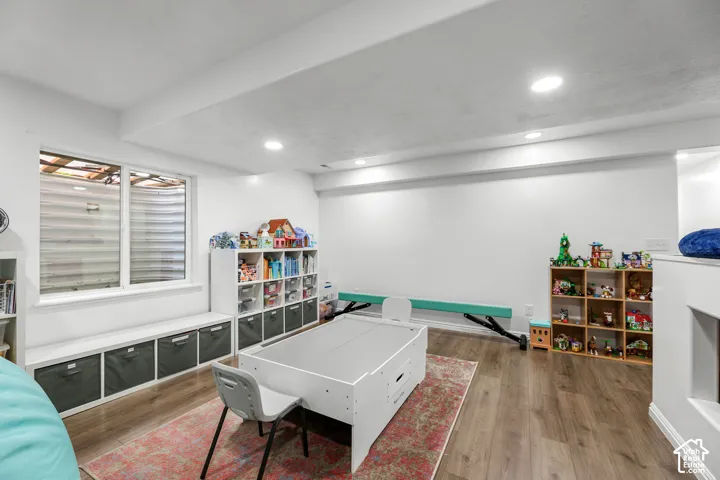 Recessed lighting, wood-finish flooring, white walls, built-in shelving, and a large window