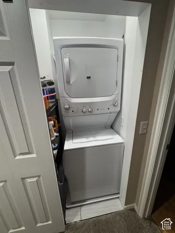 White stacked washer and dryer unit with a tiled floor base