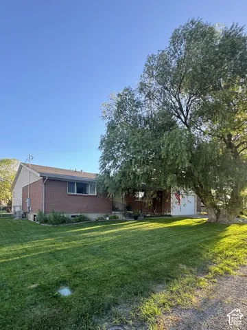 Brick and siding exterior with mature trees and a manicured lawn