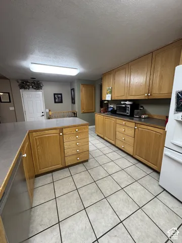 Kitchen with wood-finish cabinetry, light-toned countertops, and tile flooring
