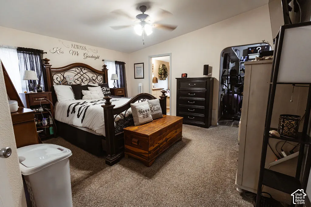 Carpeted flooring, ceiling fan with integrated lighting, and an arched doorway