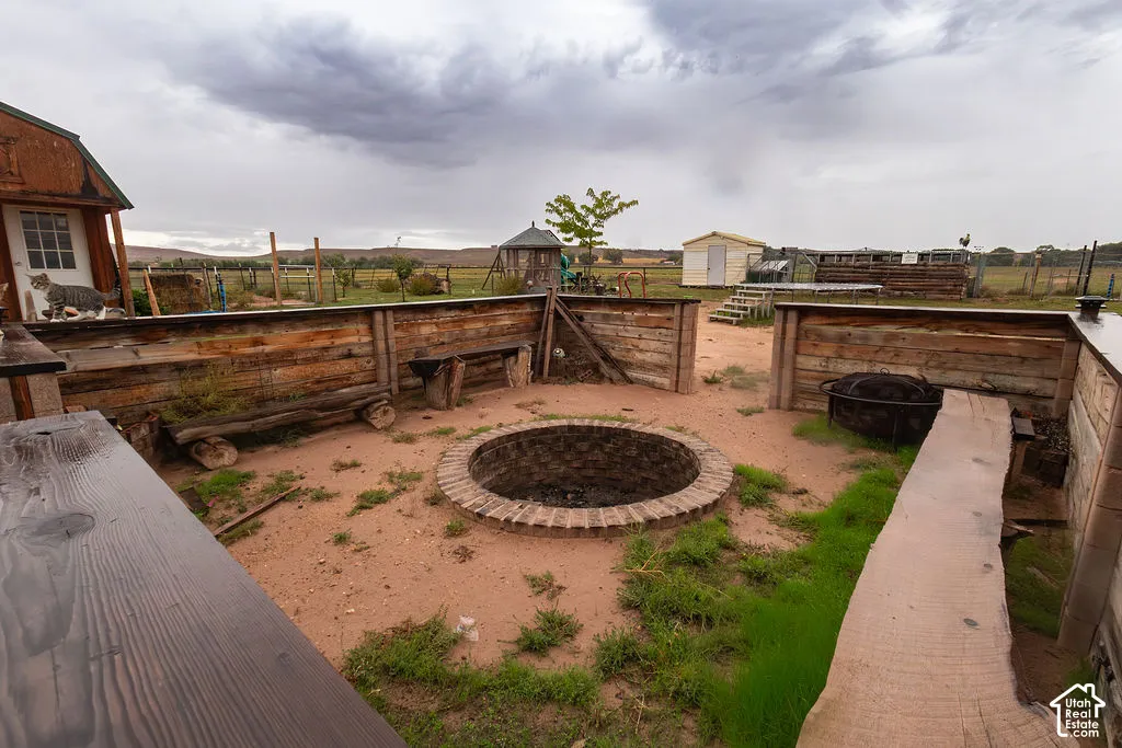 Outdoor fire pit area featuring a brick-lined fire pit, surrounding wood-finish retaining walls, and integrated log benches