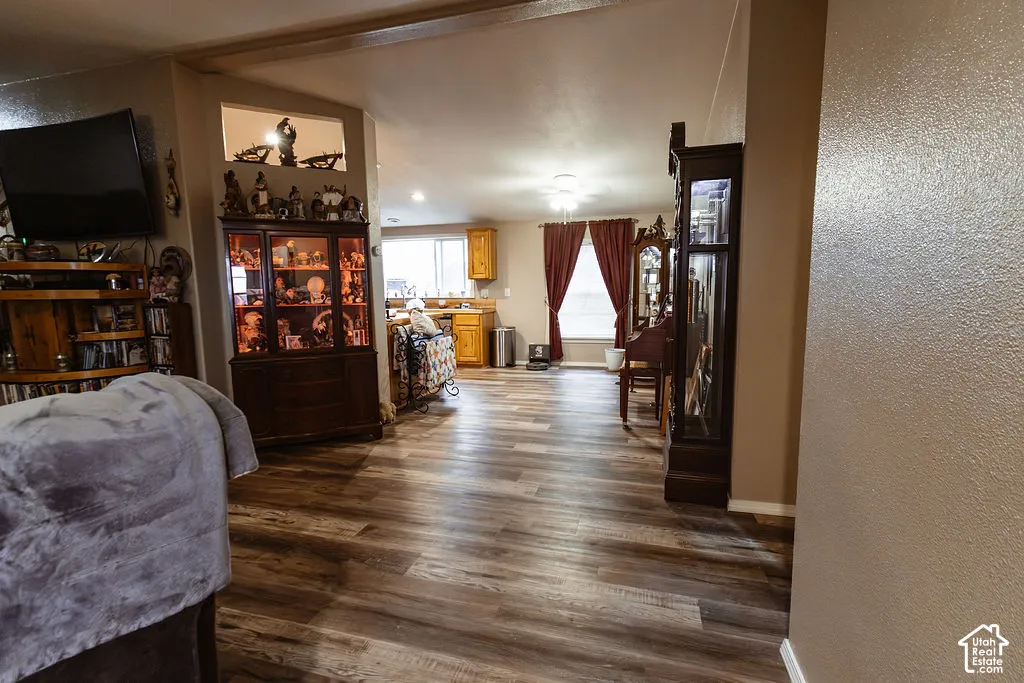 Wood-finish flooring throughout, with a wide entryway into the kitchen featuring wood cabinetry and a window