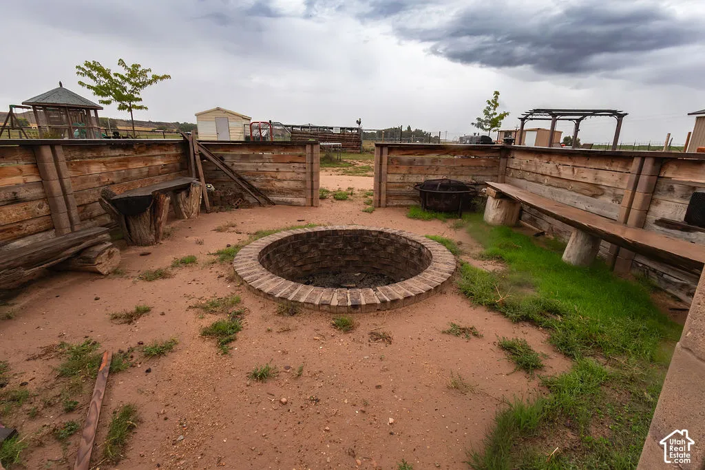 Outdoor gathering area featuring a brick-lined fire pit, built-in wooden benches, and rustic wood paneling