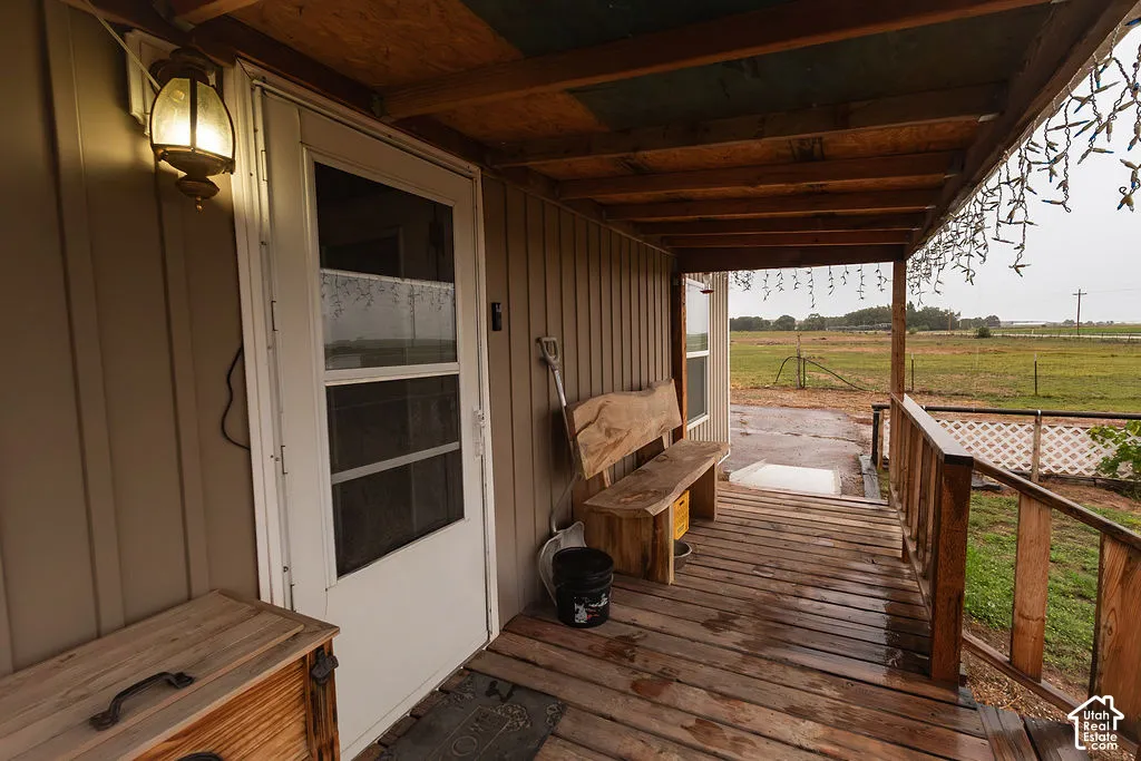 Covered wood-plank porch with wood railings and an outdoor wall lantern