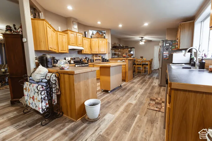 Kitchen featuring wood-finish flooring, wood cabinetry, recessed lighting, and a stainless steel refrigerator