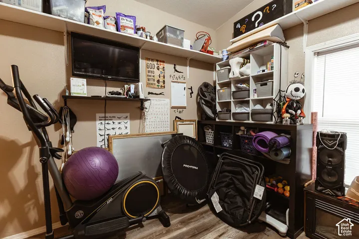 Built-in shelving for organized storage, warm wall color, wood-finish flooring, recessed window, and wall-mounted television