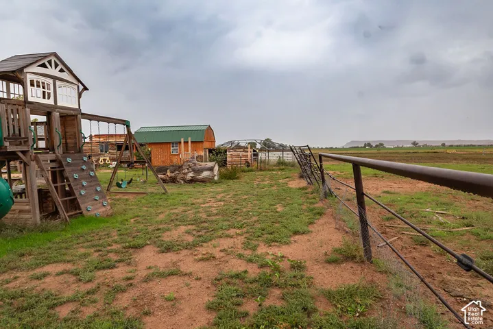Expansive outdoor space featuring a playset with a rock wall, swing set, and slide
