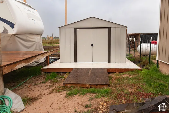 Metal storage shed with double doors on a concrete pad with a wood ramp. Power