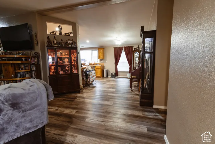 Wood-finish flooring throughout, with a wide entryway into the kitchen featuring wood cabinetry and a window