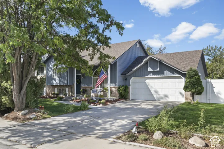 Multi-level residence featuring new vertical siding, attached two-car garage, and a concrete driveway