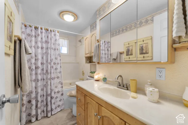 Bathroom featuring a built-in vanity with light wood cabinetry, an integrated sink, and an expansive medicine cabinet