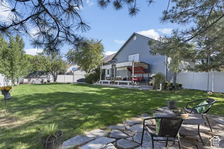 Expansive backyard with a manicured lawn, established trees, a flagstone patio, and Trex deck